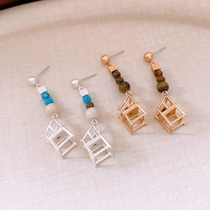Detailed view of creative silver and gold chair pendant earrings with decorative beads