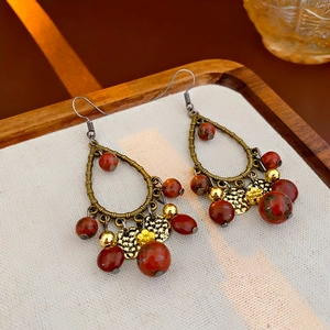 Close-up of bohemian tassel earrings with bronze frames and marbled reddish-brown beads