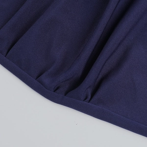 Detailed close-up of dark blue knitted fabric with elegant twisted knot and ruched design