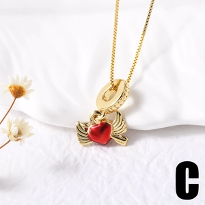 Detail of gold winged heart necklace with red pendant on white fabric background