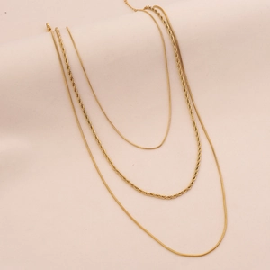 Detail of 3-layer gold necklaces featuring snake and twisted chain texture on beige fabric