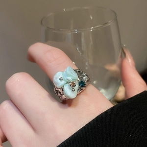 Detailed view of silver hammered flower ring with blue shell and tiny crystals on finger