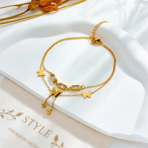 Detail of gold double-layer butterfly anklet with zircons and tassel on white stone