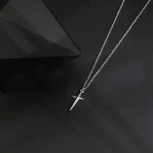 Close-up of a silver cross necklace on a modern black block base with a minimalist aesthetic