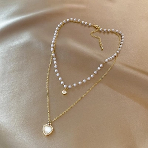 Detail view of double-layered pearl necklace with a heart-shaped cat-eye stone pendant