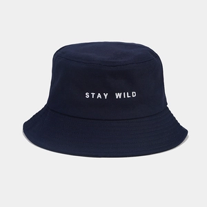 Détail de la broderie Stay Wild blanche sur un chapeau bob en toile bleu foncé