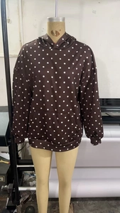 Détail d'un sweat à capuche marron à pois blancs avec une poche kangourou frontale