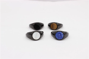 Top view of four minimalist signet rings with black bands and colorful round stone inlays
