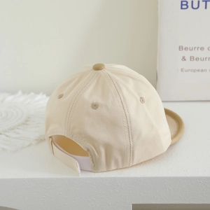 Detailed close-up of light beige baby baseball cap with cotton texture and adjustable strap