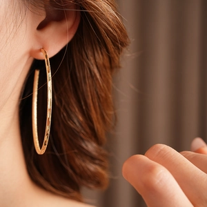 Primo piano di una modella con orecchini a cerchio placcati in oro dallo stile minimal