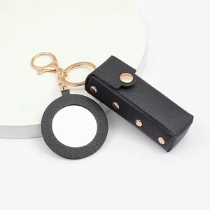 Detail of black leather lipstick pouch keychain with gold hardware and small mirror