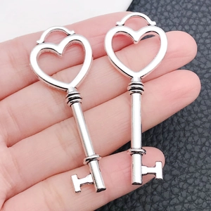 Detailed view of silver heart-shaped key charms with ornate crown and hollow patterns