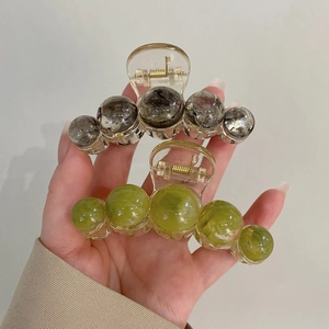 Detail of gradient planet sphere hair claw clips in dark grey and light green finish