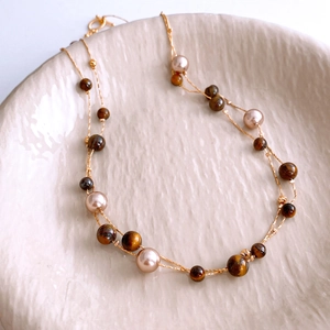 Detail of vintage layered necklace with brown tiger eye beads and champagne pearls in tray