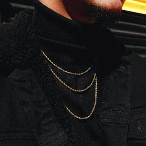 Close-up of triple-layered 18K gold-plated rope chains with textured twist on black fabric