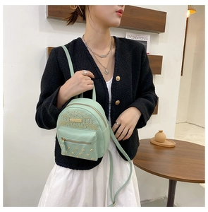 Detail of mint green mini backpack featuring gold rivet accents and earphone port