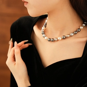 Close-up of elegant gradient pearl necklace on model featuring white and grey beads