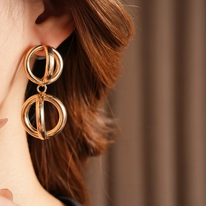 Nahaufnahme goldener geometrischer Doppelring-Ohrringe am Model für trendigen Stil