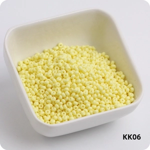 Macro shot of 3mm light yellow glass seed beads for DIY jewelry in a white ceramic bowl