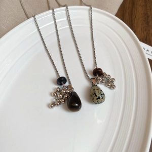 Macro view of teardrop tiger eye and dalmatian jasper pendants with silver beads