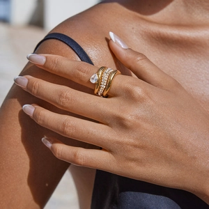 Elegant gold layered rings set with teardrop zircon worn by a model in sunlight