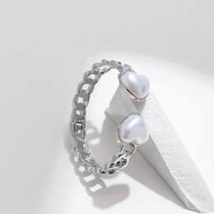 Detail of silver chain bracelet with twin heart-shaped pearls on a geometric block