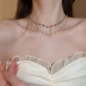 Nahaufnahme der zweilagigen Goldkette mit bunten Edelsteinen und Perle am Model