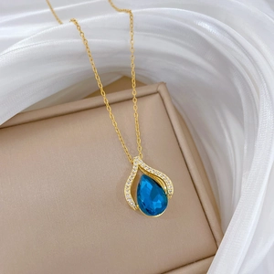 Close-up of a blue water-drop gemstone necklace with crystals on beige box