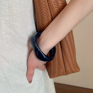 Close-up of a wide dark blue acrylic resin bangle with a smooth polished finish