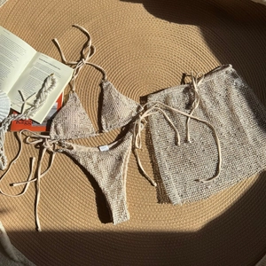 Detailed macro view of beige three-piece crochet mesh bikini with textured knit fabric details