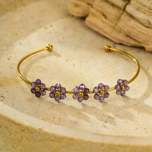 Dettaglio del bracciale rigido dorato con petali di fiori in zircone viola su base ruvida
