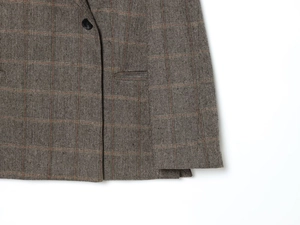 Detail shot of grey plaid tweed blazer with herringbone weave and a single black button