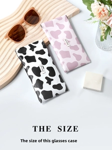 Detail of cow print leather glasses pouches with snap closure on a wooden tray