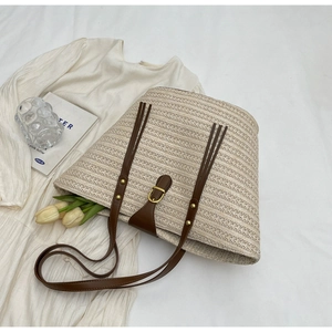 Flat lay of a woven straw tote bag with brown PU straps and decorative tulips