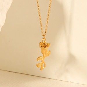 Detailed macro shot of a 3D golden rose pendant on a delicate link chain necklace