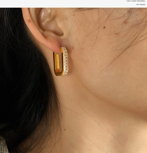 Close-up of woman wearing gold rectangular earrings with clear zircon stones