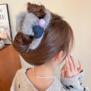 Detail of plush grey heart flower hair claw clip on model's hair in elegant style