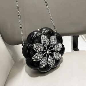 Detailed view of a black flower evening bag with sparkling rhinestones and silver chain