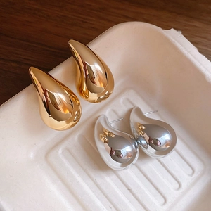 Macro shot of gold and silver teardrop earrings with polished finish on a display tray