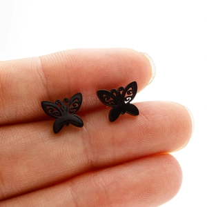 Close-up of small matte black hollow butterfly stud earrings held on fingertips