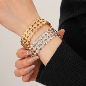Close-up of gold and silver layered woven cuff bracelets on a model's wrist