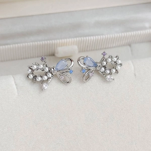 Detailed macro view of bowknot earrings with blue gemstones and pearls in jewelry box