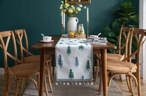 Detail of pine and deer embroidery on linen table runner with elegant tassels