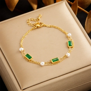 Detail of 18K gold-plated layered bracelet with green gems and pearls on velvet box