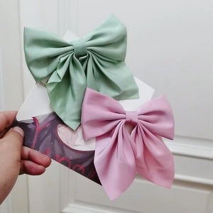 Detail of silk satin bow hair clips in green and pink colors on decorative card