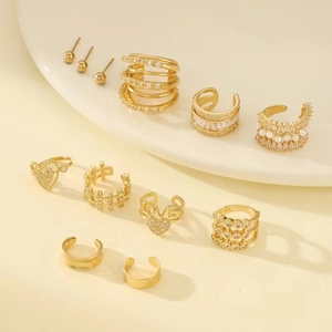 Detailed set of golden heart and LOVE letter ear cuffs with zircons on white plate