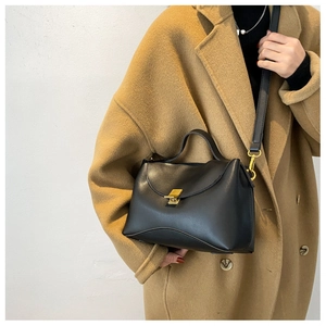 Detail of a black leather handbag with golden square clasp and adjustable shoulder strap