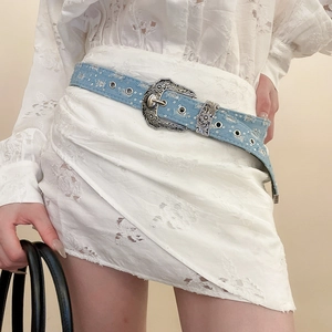 Detail showing vintage blue denim belt with carved silver western buckle and metal studs
