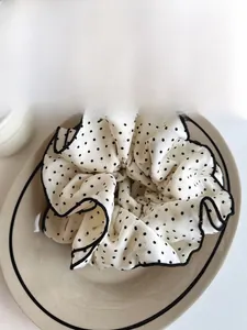Macro detail of polka dot hair scrunchie with pleated edges and premium piping