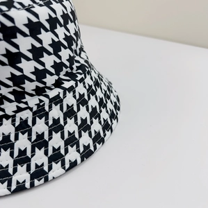 Close-up of black and white houndstooth bucket hat showing stitching and canvas texture